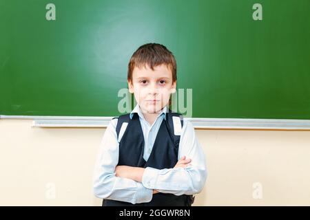 Drôle d'écolier près de la commission scolaire verte dans la salle de classe. Enfant de l'école primaire. Retour à l'école. Banque D'Images