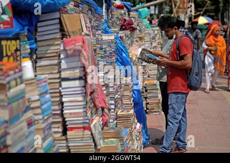 Dhaka, Bangladesh. 3 septembre 2021. Un homme lit un livre sur des livres empilés qui ont été mis aux enchères à des prix très bas sur le marché extérieur en raison de la fermeture des librairies en raison du manque de ventes en raison de la situation Covid-19. Les anciennes librairies de la capitale Newmarket ont subi des pertes dues à la fermeture des établissements d'enseignement depuis longtemps en raison de la prévalence de Covid-19. Le 3 septembre 2021 à Dhaka, au Bangladesh. Credit: EYEPIX Group/Alamy Live News Credit: EYEPIX Group/Alamy Live News Banque D'Images