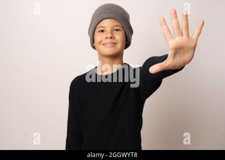 Portrait d'un jeune garçon souriant portant un chapeau de laine sur fond blanc Banque D'Images