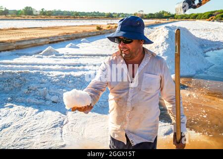 20 août 2021 - Faro, Portugal: Un ouvrier montrant un cristal de sel de mer pendant la récolte de sel aux salines naturelles Banque D'Images