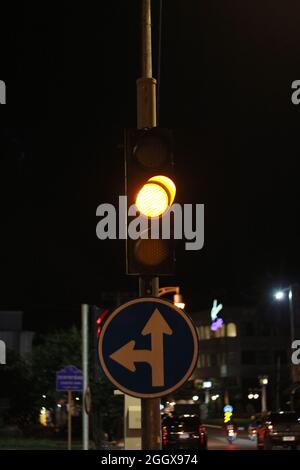 Feux de signalisation avec lumière jaune, panneau de signalisation tournez à gauche et Vas-y en ville. Banque D'Images