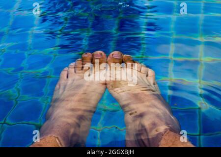 détendez-vous, des pieds d'homme dans la piscine sous l'eau Banque D'Images