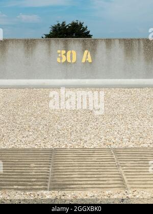 Peinture jaune en acier numéro 30A sur un mur de mer en béton Banque D'Images