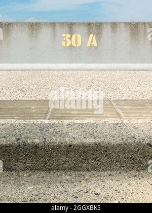 Peinture jaune en acier numéro 30A sur un mur de mer en béton Banque D'Images