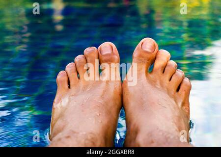 détendez-vous, des pieds d'homme dans la piscine sous l'eau Banque D'Images