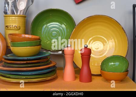 Des assiettes colorées, des bols et des salières et poivrières se trouvent dans la cuisine et dans le magasin de produits pour la restauration. Mestoli signifie louche en italien. Banque D'Images
