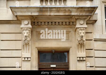 Une grande entrée à un bâtiment en pierre. Têtes de lions de grès sculptées. Banque D'Images