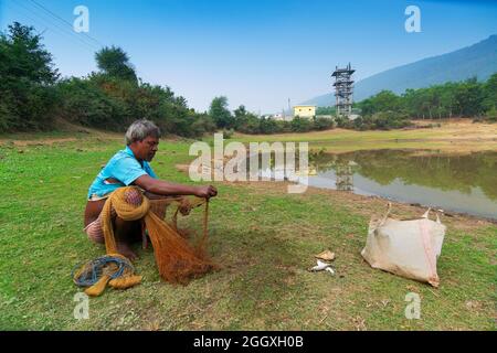 Gar Panchkot, Purulia , Bengale-Occidental, Inde - 23rd décembre 2015 : Un pêcheur solitaire comptant les poissons capturés de l'étang. Inde ayant de nombreux étangs . Banque D'Images