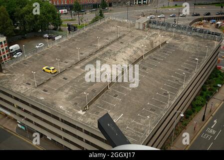 Un parking presque vide à Birmingham. Une voiture jaune vif solitaire au dernier étage. Banque D'Images