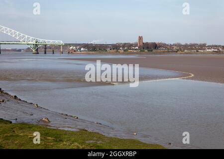 Le Mersey Tidal Bore approche du parc communautaire de Wigg Island à Runcorn avec le pont Silver Jubilee en arrière-plan Banque D'Images