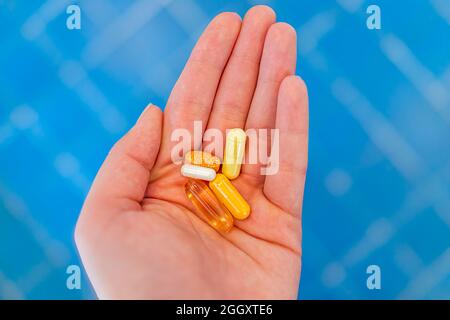 Gros plan de la jeune femme main tenant des pilules de médicament de supplément dans la paume comme la vitamine c et b et l'huile de poisson Banque D'Images