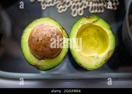 Plan de dessus a posé près du cultivar du sud de la Floride de grand vert frais brut basse graisse avocats tranchés en deux avec grande fosse à semences sur la table de cuisine Banque D'Images