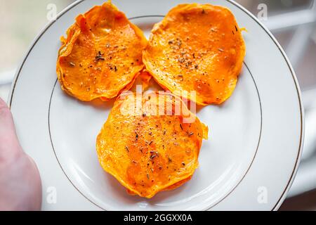 Macro gros plan de la personne tenant une assiette blanche avec de la courge de noyer cendré cru ravioli déshydraté farci farci farci farci farci farci avec des tranches, olive extra vierge Banque D'Images