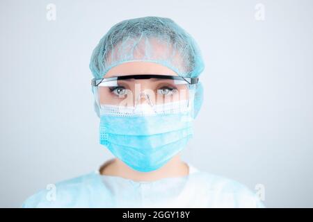 Infirmière dans une robe médicale, un masque et des gants de protection avec des lunettes transparentes Banque D'Images