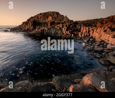 Coucher de soleil sur les colonnes de basalte de la chaussée des géants dans le comté d'Antrim, en Irlande du Nord Banque D'Images