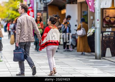 Nara, Japon - 14 avril 2019: Gens touristes candid couple marchant sur la rue trottoir dans le centre-ville vers le parc avec des magasins et panneau Banque D'Images