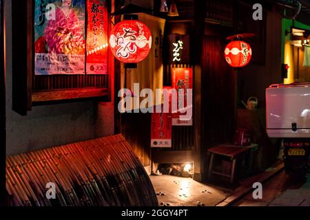 Kyoto, Japon - 16 avril 2019 : lanternes en papier rouge illuminant l'affiche de geisha dans la nuit sombre, sans personne à l'entrée du restaurant Banque D'Images