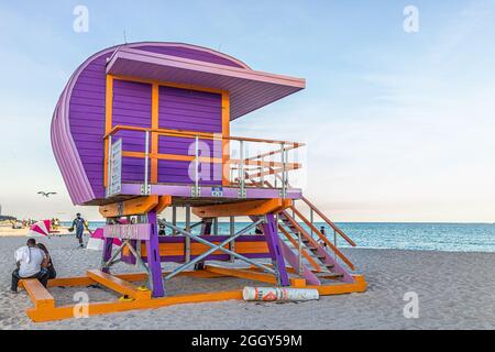 Miami Beach, États-Unis - 21 janvier 2021 : station de construction de huttes de sauveteurs orange violet avec des gens à South Beach près de l'océan Atlantique au coucher du soleil avec bleu clair Banque D'Images