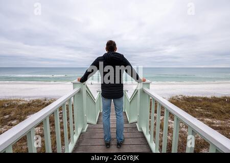 Pavillon vert de bord de mer promenade passerelle escalier menant à la mer du golfe du Mexique avec l'arrière du jeune homme par rampe dans la vue de l'architecture de la Floride Banque D'Images