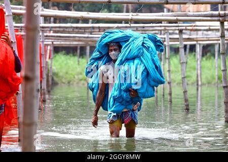 Narayanganj, Bangladesh. 03ème septembre 2021. Un ouvrier bangladais recueille des tissus peints après les avoir séchés sous le soleil dans une usine de teinture à Narayanganj, près de la capitale Dhaka. La plupart des travailleurs souffrent de maladies de la peau par contact constant avec les produits chimiques utilisés pour teindre le tissu, en raison de l'absence de mesures de précaution appropriées. Le 03 septembre 2021 à Narayanganj City, Bangladesh. (Photo de Harun-or-Rashid / Groupe Eyepix) Credit: EYEPIX Group/Alamy Live News Banque D'Images