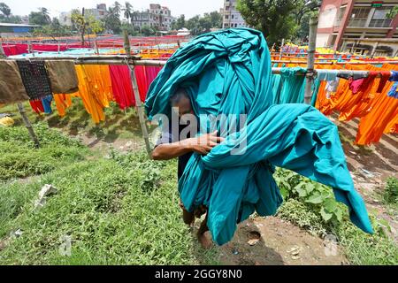 Narayanganj, Bangladesh. 03ème septembre 2021. Un ouvrier bangladais recueille des tissus peints après les avoir séchés sous le soleil dans une usine de teinture à Narayanganj, près de la capitale Dhaka. La plupart des travailleurs souffrent de maladies de la peau par contact constant avec les produits chimiques utilisés pour teindre le tissu, en raison de l'absence de mesures de précaution appropriées. Le 03 septembre 2021 à Narayanganj City, Bangladesh. (Photo de Harun-or-Rashid / Groupe Eyepix) Credit: EYEPIX Group/Alamy Live News Banque D'Images