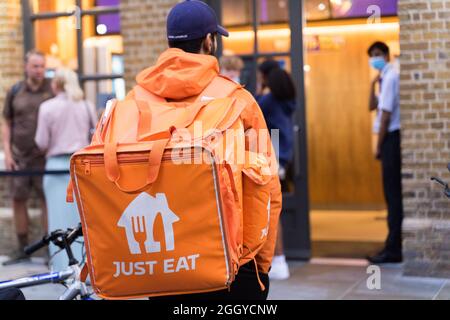 Le livreur transporte le sac à dos JUSTE à MANGER devant le restaurant McDonalds à London Bridge en Angleterre Banque D'Images