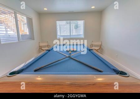 Table de billard bleue avec queues de billard croisées et boules de billard Banque D'Images