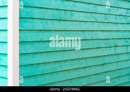 L'extérieur d'un vert sarcelle brillant étroit en bois horizontal mur de panneau de bois d'une maison d'époque. La garniture du bâtiment est blanche. Banque D'Images