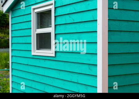 L'extérieur d'un mur de panneaux de bois horizontal étroit vert vif d'une maison. La garniture du bâtiment est blanche. Banque D'Images