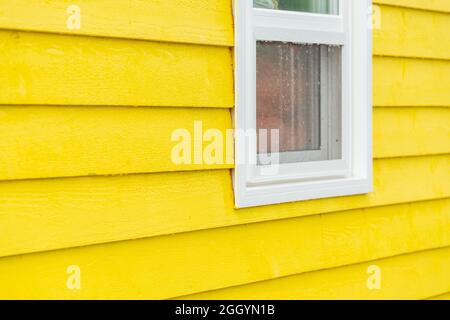 L'extérieur d'un vert sarcelle brillant étroit en bois de mur horizontal de panneau d'une maison avec une fenêtre en vinyle. La garniture des vitres est blanche. Banque D'Images