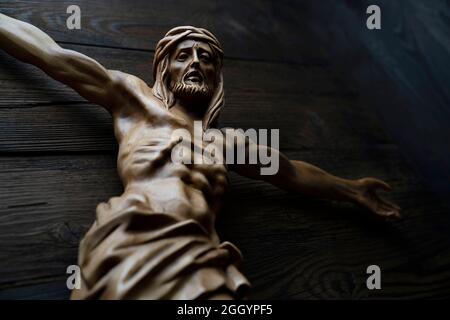 Figurine Jésus Cruciefied isolée sur une table rustique marron foncé. Banque D'Images