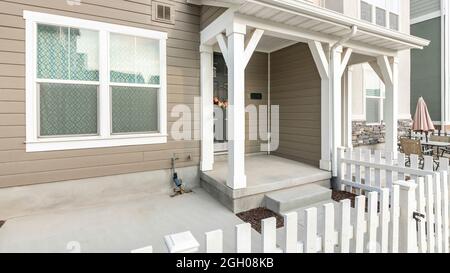 Pano extérieur d'une maison avec porte avant sombre avec couronne et clôture en bois et porte Banque D'Images