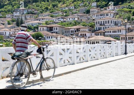 Homme local avec un vieux vélo traversant le vieux pont traditionnel dans la ville de berat, en Albanie, Banque D'Images