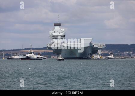 Remorqueurs positionner le porte-avions HMS PRINCE DE GALLES dans le port. Le bateau part pour d'autres essais en mer Banque D'Images
