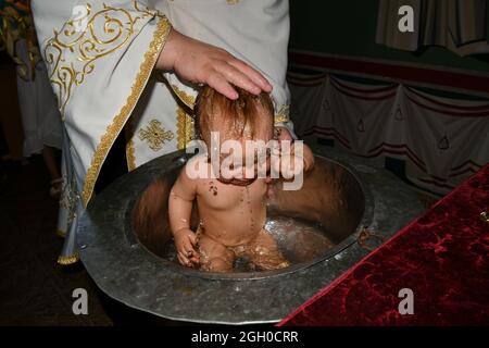 Un prêtre orthodoxe baptise un bébé Banque D'Images