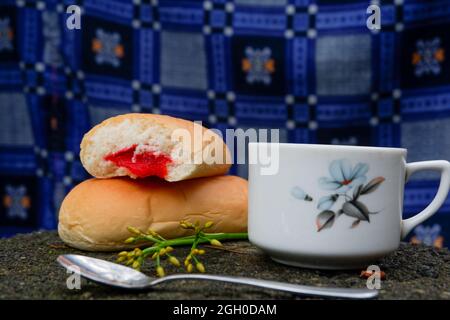 Gros plan de pain avec confiture de fraise avec une tasse de thé et une cuillère à fond bleu Banque D'Images