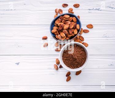 La poudre de cacao et les fèves de cacao sur fond de bois. Morceaux de chocolat concassé et herbes aromatiques . Banque D'Images