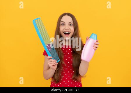 surprise teen fille a de longs cheveux tenir brosse et lotion, foyer sélectif, habitude quotidienne. Banque D'Images