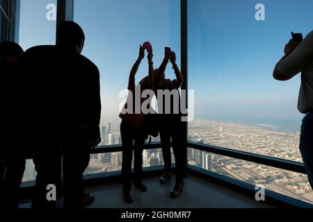 Un couple de touristes prenant des photos, se selfies avec leur téléphone sur une terrasse d'observation au Burj Khalifa. À Dubaï, Émirats arabes Unis. Banque D'Images