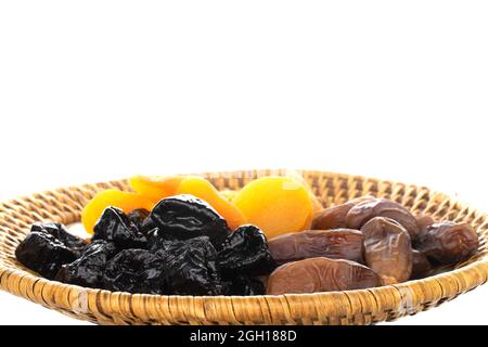 Plusieurs dattes appétissantes, abricots séchés, pruneaux dans une plaque de céramique, gros plan, isolés sur blanc. Banque D'Images