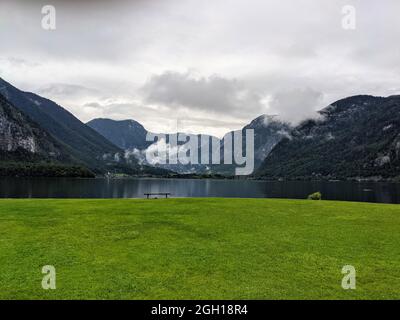 Lac alpin Hallstatter Voir sous la pluie avec un banc et de l'herbe verte Banque D'Images