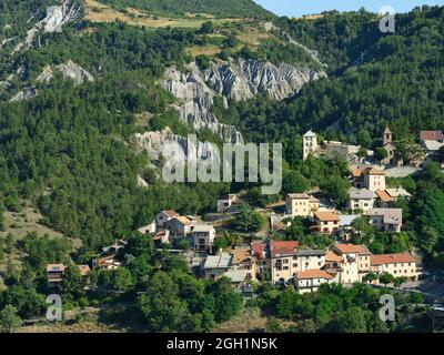 VUE AÉRIENNE. Village de Théus avec son arrière-plan de badlands et de nombreux hoodoos. Vallée de la Durance, Hautes-Alpes, France. Banque D'Images