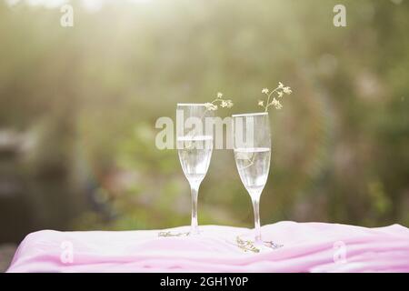 Champagne avec fleurs sauvages à l'extérieur. Pique-nique photo sur la nature avec lumière du soleil. Concept de célébration de la vie et de la solitude. Verres avec champagne. Qual. Élevée Banque D'Images