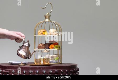 Un processus consistant à déguster un thé de l'après-midi avec un assortiment de desserts et d'en-cas sur un magnifique ensemble de thé de style marocain. Banque D'Images