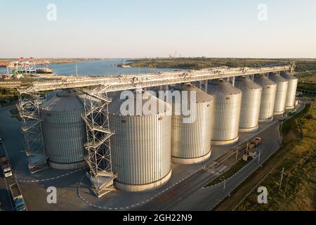 Odessa, Ukraine - Аugust 14, 2021: Terminaux céréaliers du port commercial maritime moderne. Silos pour le stockage du grain dans les rayons du soleil couchant, vue de dessus de Quadco Banque D'Images