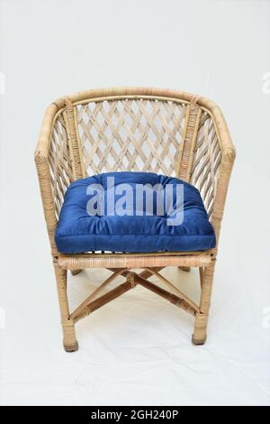 Chaise en rotin avec coussins bleus, fond blanc, mise au point douce Banque D'Images