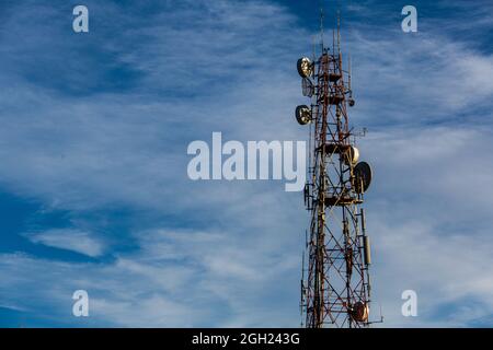 Poteau de télécommunication avec plusieurs types d'antennes dans le ciel bleu et les nuages dans la lumière ensoleillée jour avec l'espace de copie. Banque D'Images