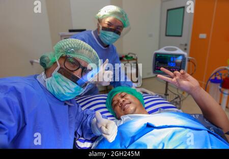 Équipe de médecins de chirurgien et de patient retrouvé heureux et lever les mains pour les pouces vers le haut et montrer signe de victoire après terminé et succès dans la chirurgie dans l'op Banque D'Images