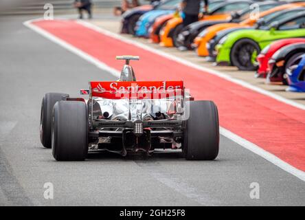 Une voiture McLaren F1 Grand Prix passe devant les voitures de sport McLaren sur le circuit Silverstone lors d'une réunion du McLaren Owners Club Banque D'Images