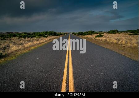 Route de campagne convergente avec dunes et ciel nuageux Banque D'Images